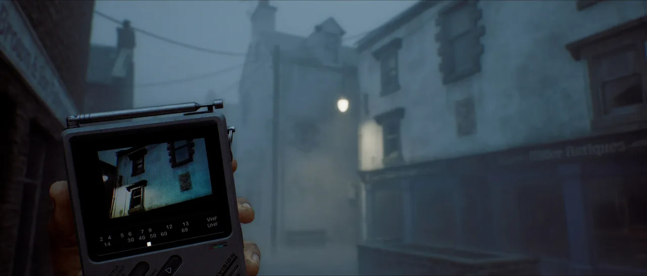 First-person view of a hand holding a small handheld television showing a house, on a foggy street.