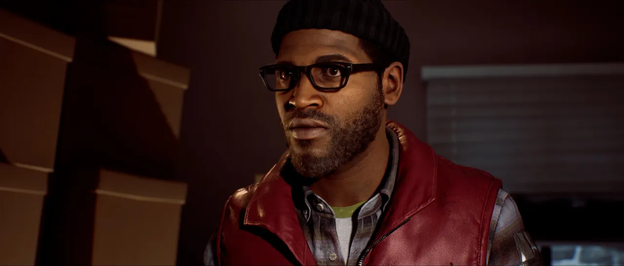 A man in a red vest indoors among cardboard boxes, lit warmly.