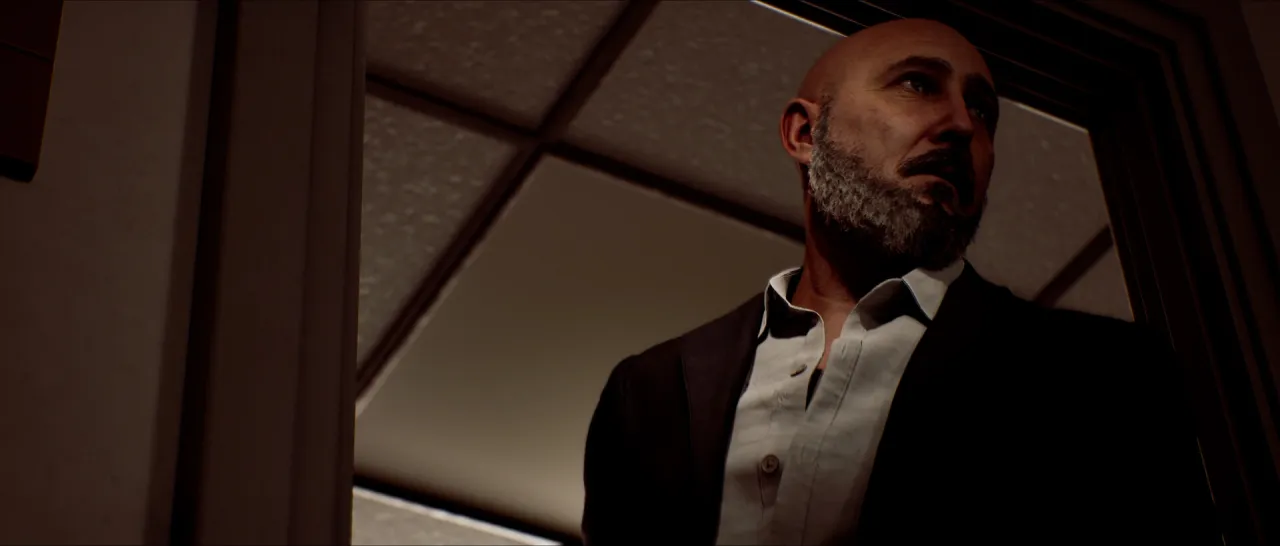 A bald, bearded man in a dark jacket seen from below in a doorway.