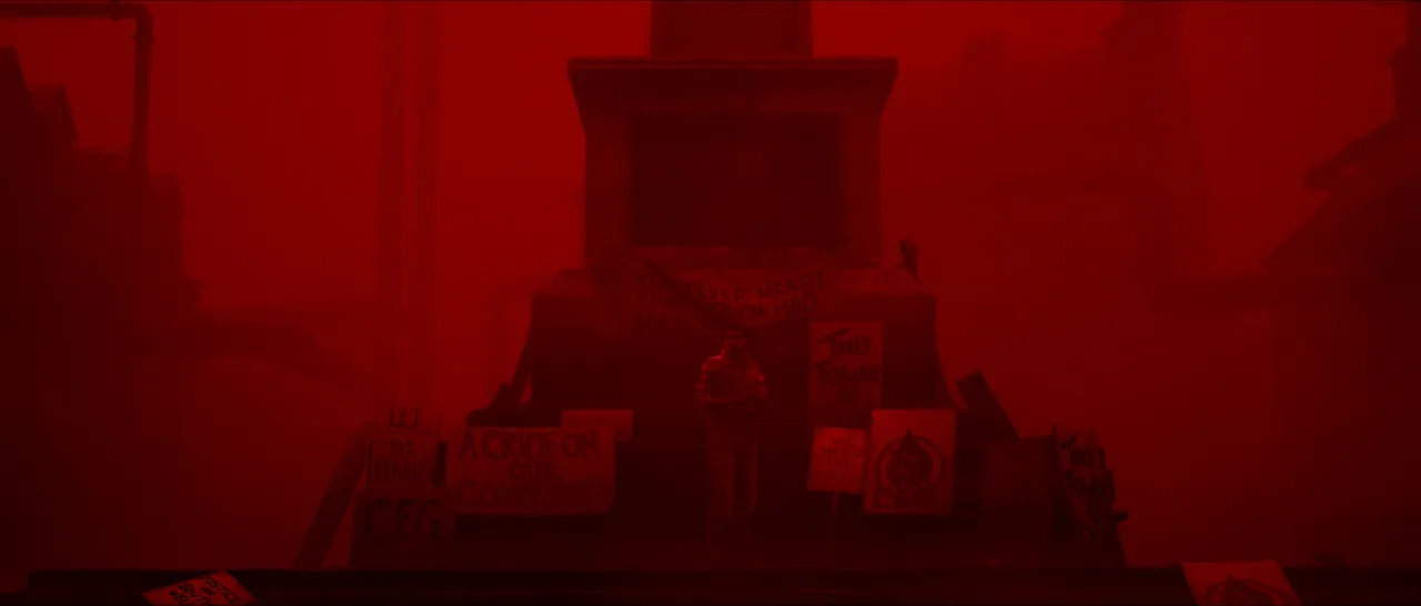 A monument in a square washed in red light.